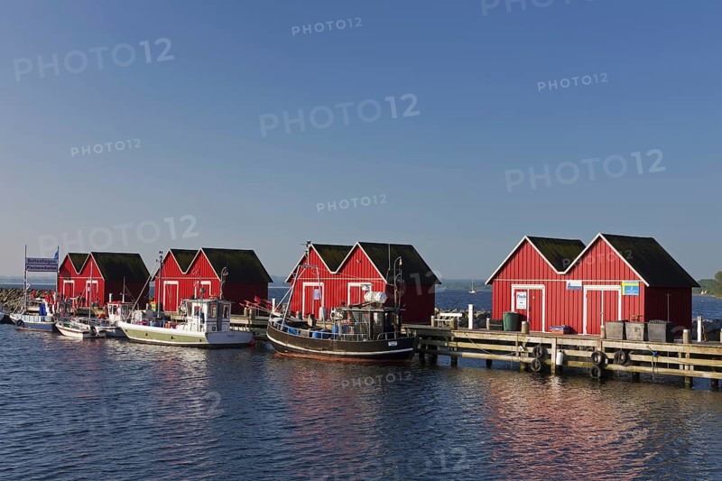 Fishing boats moored in front of red wooden huts in the harbour of Boltenhagen along the Baltic Sea