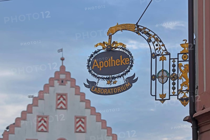 Nose shield of the court pharmacy with golden inscription Laboratorium and blurred stepped gable of the town hall