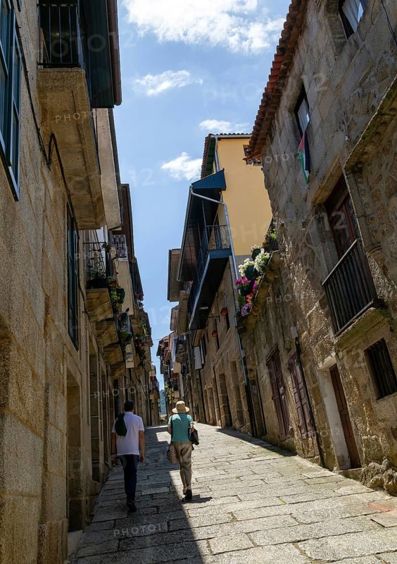 Two people walking past houses on steep narrow street in medieval town