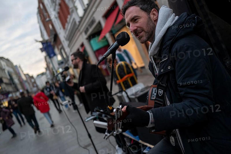 Andrew Glover of Irish pop group Keywest playing in Grafton Street with lead singer Andrew Kavanagh in the back ground. Dublin