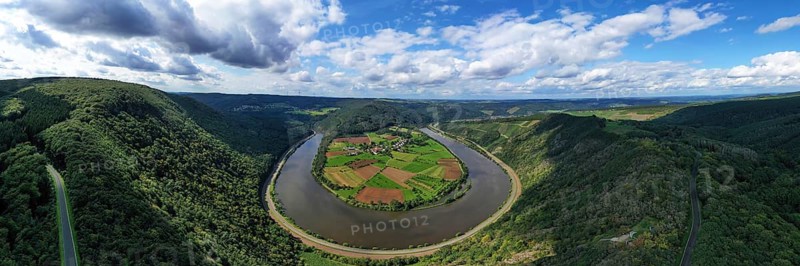 River bend of the Saar. The river winds through the valley and is surrounded by green hills and forests. Serrig