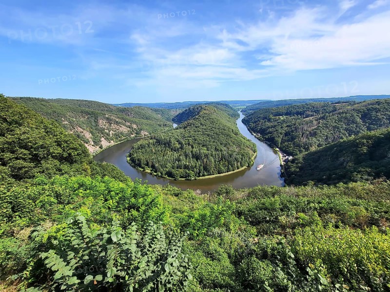 Aerial view of the Saar Loop. The Saar winds through the valley and is surrounded by green forests. Orscholz