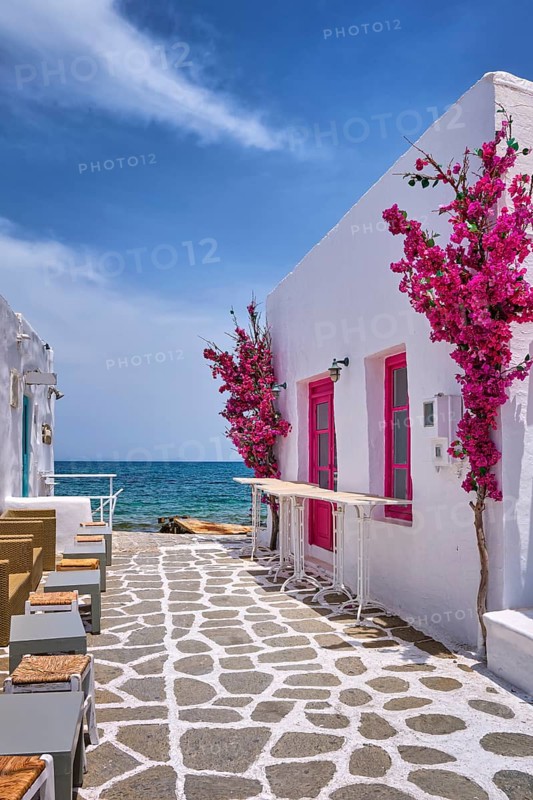 Beautiful street of Greek island town open right to seafront on sunny summer day. Whitewashed houses