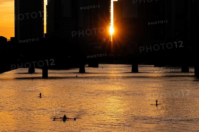 Some stand-up paddlers paddle on the Main in Frankfurt shortly in front of sunset