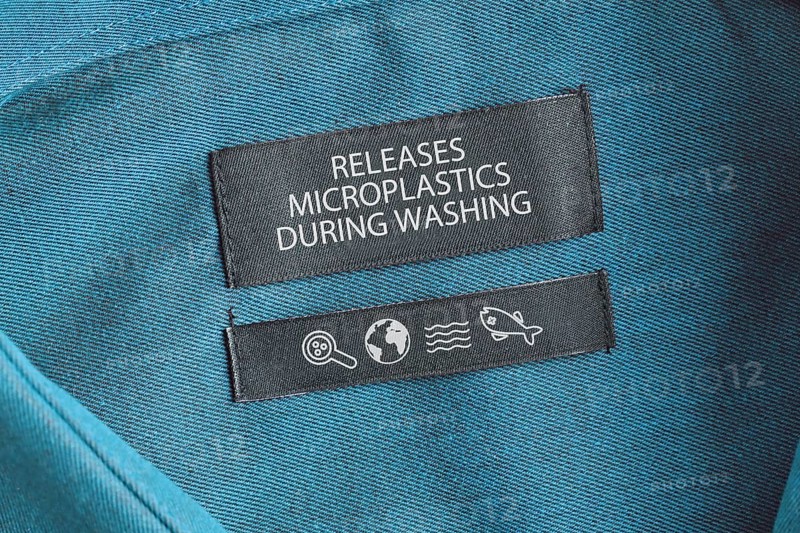 Clothing label saying 'Releases microplastics during washing'. Concept for synthetic clothing fiber pollution problem