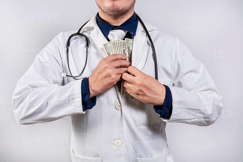 Dishonest doctor putting money in pocket. Medical bribery concept