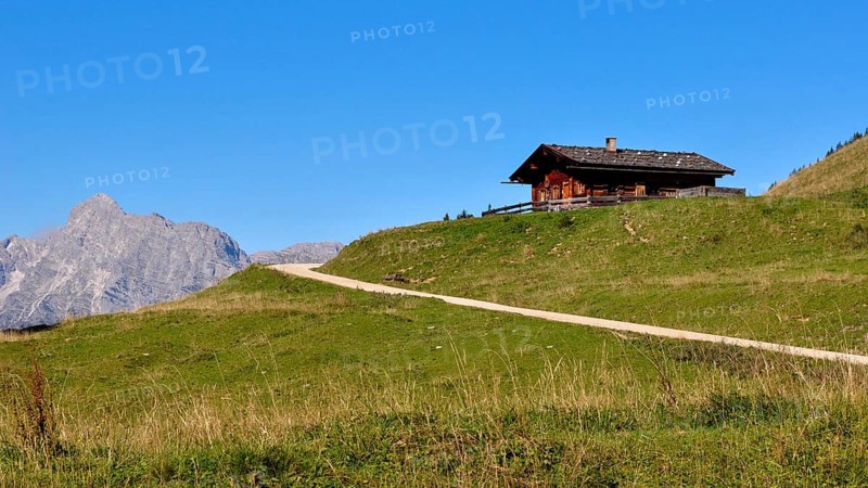 One of the rustic alpine huts on the Kallbrunnalm in the Berchtesgaden Alps with the Loferer Steinberge in the background