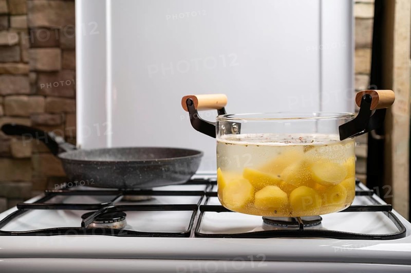 Boiling potato in transparent glass pot on a gas stove