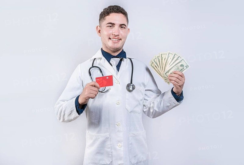 Happy latin doctor holding credit card and money isolated. Cheerful doctor holding money and credit cards