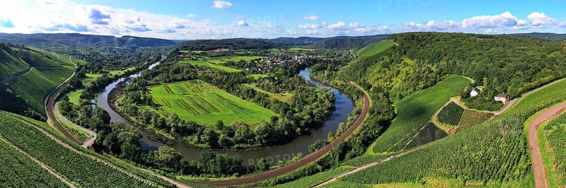 Wiltinger Saarbogen. The river winds through the valley and is surrounded by vineyards and green forests. Kanzem