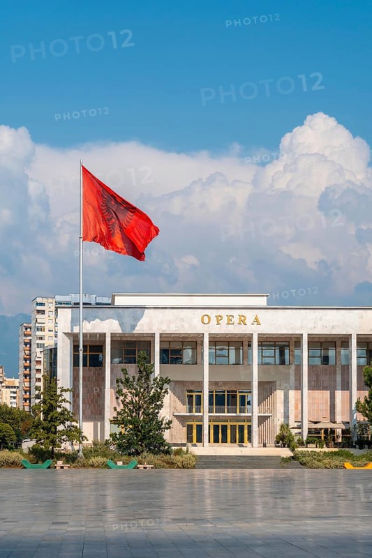 Palace of Culture or Opera on Skanderbeg Square in Tirana and the flag of Albania moving in the wind