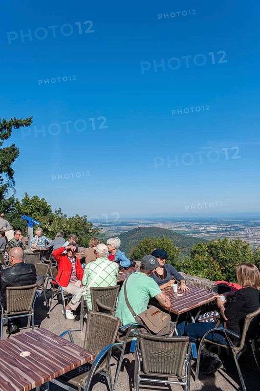 Tourists at the viewpoint in front of the Chateau du Haut Koenigsbourg. In the background the Upper Rhine Plain and the hilly landscape of the Black Forest