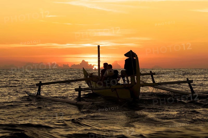 Small boat with outrigger in the sunrise