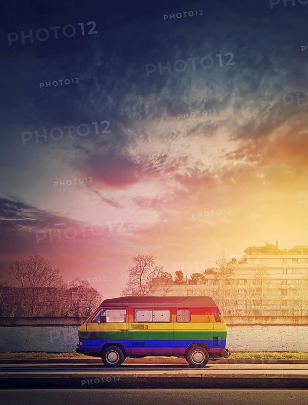 Rainbow painted vintage van parked on the edge of the street in the sunset light background. Lgbtq colors