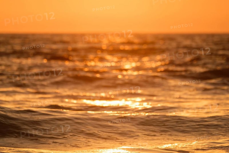 Ocean on sunset backlit with sun defocused blurred background