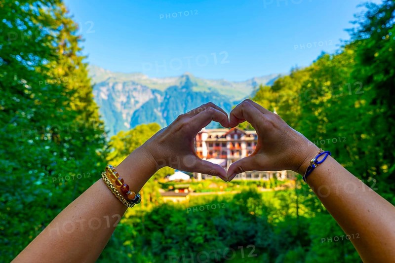 Woman Making a Heart Shape in Front of The Historical Grandhotel Giessbach on the Mountain Side in Brienz