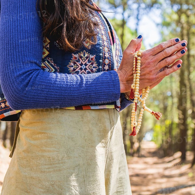 Close up of clasping hands holding a japa mala