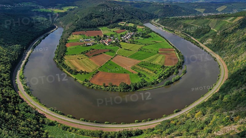 River bend of the Saar. The river winds through the valley and is surrounded by green hills and forests. Serrig