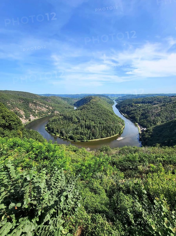 Aerial view of the Saar Loop. The Saar winds through the valley and is surrounded by green forests. Orscholz
