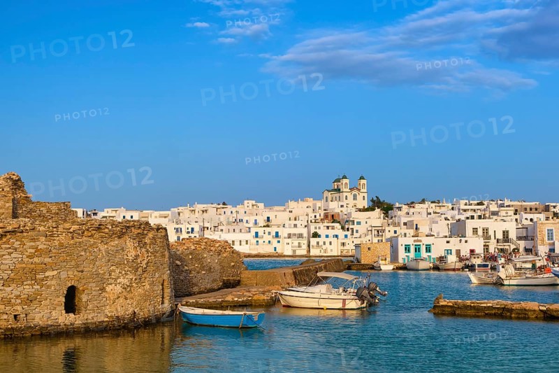 Traditional Greek whitewashed houses and church of Dormition of Mother of God as local landmark on hilltop by seafront on sunny day