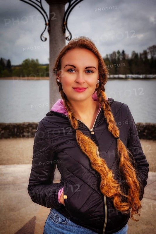 Portrait of a young woman with long braids dressed in an anorak in rainy weather