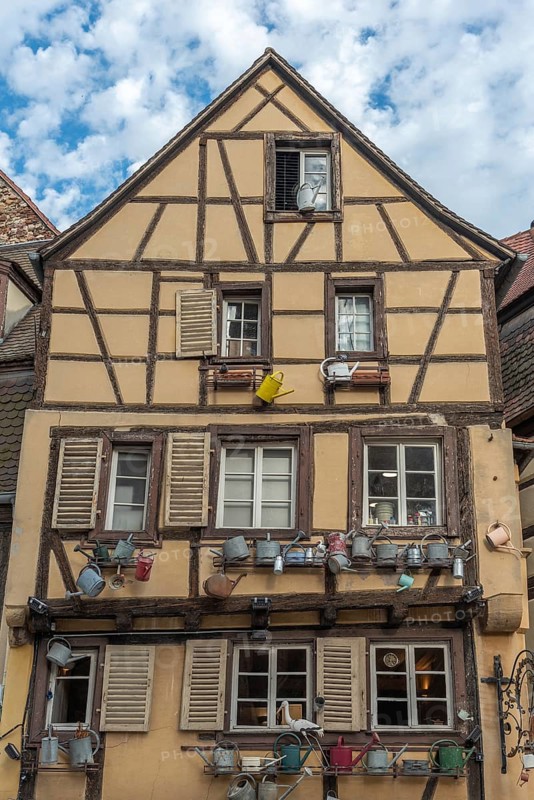 Facade of a traditional Alsatian house decorated with old water jugs