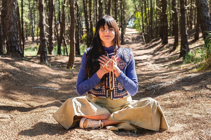 Portrait of an adult woman meditating with folded hands on her chest