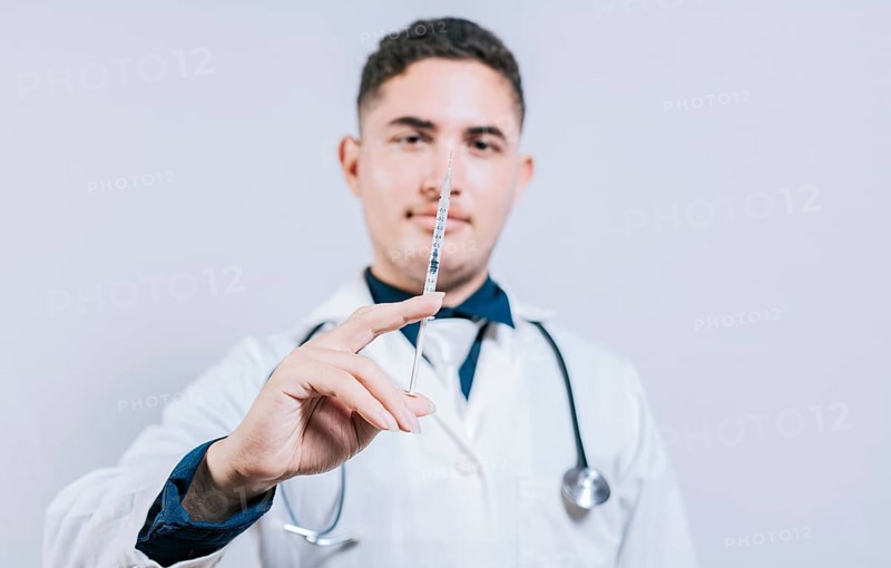 Closeup of doctor holding and showing a syringe isolated. Caucasian doctor holding a syringe on isolated background