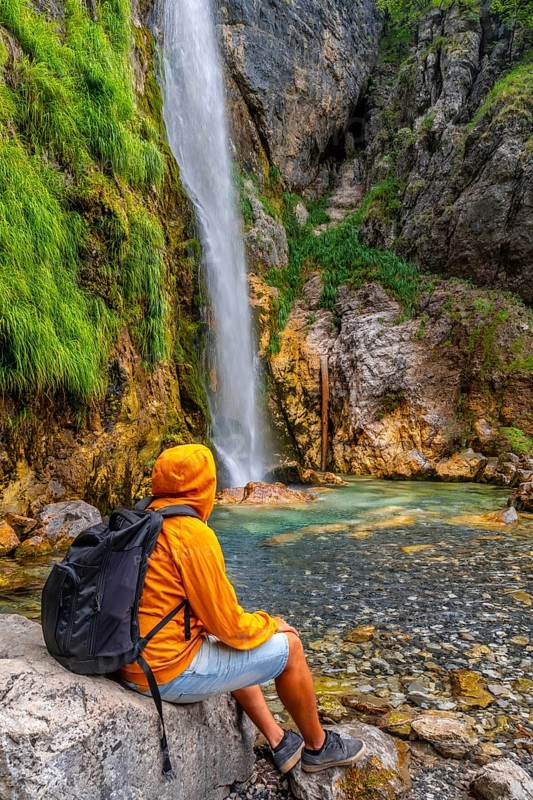 Man with backpack at Grunas waterfall in Theth national park