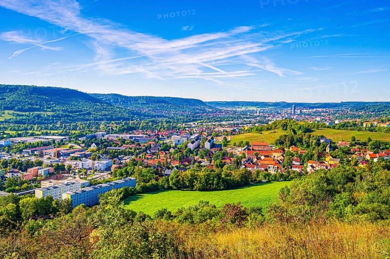 View over the city of Jena from the Galgenberg with the Kernberge in the background under blue sky and veil clouds