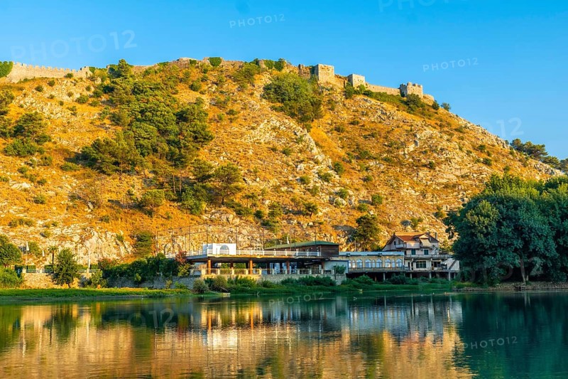 View of the Rozafa Castle on top of the mountain from a boat on a sightseeing excursion on Lake Shkoder in Shiroka. Albania