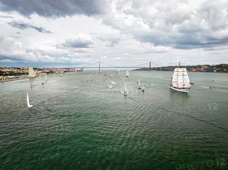 Aerial drone view of tall ships with sails sailing in Tagus river towards the Atlantic ocean in Lisbon