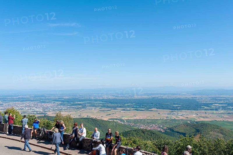 Tourists at the viewpoint in front of the Chateau du Haut Koenigsbourg. In the background the Upper Rhine Plain and the hilly landscape of the Black Forest