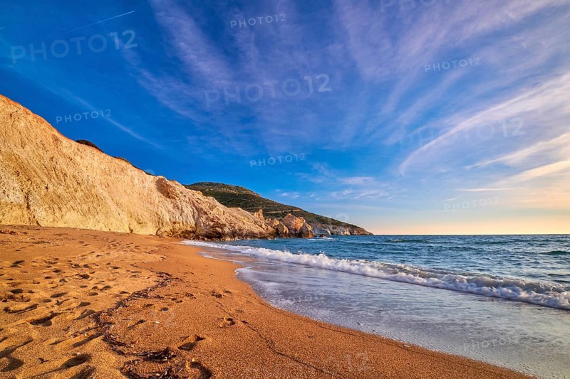 Beautiful low sun view of secluded and remote beach on sunny evening. High yellow cliffs