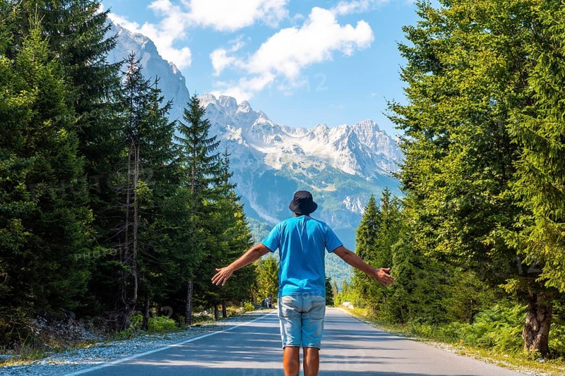 A tourist in summer walking on the road in the Valbona valley