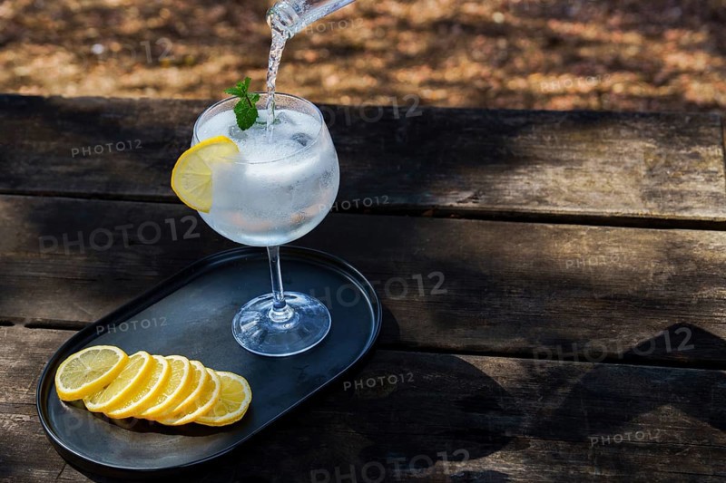 Top view of a bottle of tonic poured over a glass with ice