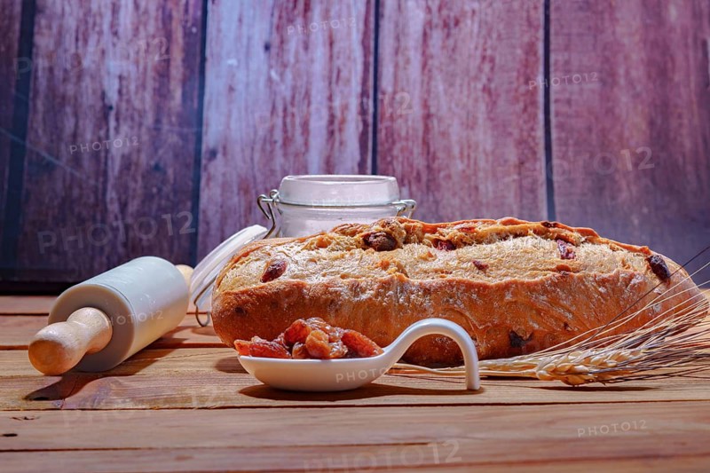 Loaf of rustic raisin bread on a wooden table with flour