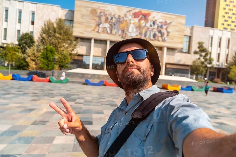 Selfie of a tourist blogger at the entrance to the National Historical Museum in Skanderbeg Square in Tirana. Albania