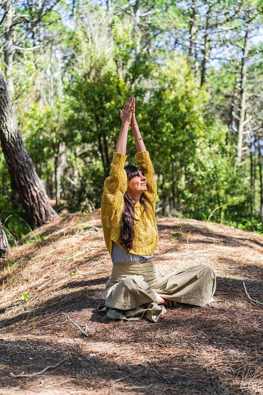 Woman about to meditate with hands clasped to the sky on the woods. Vertical shot
