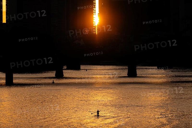 Some stand-up paddlers paddle on the Main in Frankfurt shortly in front of sunset