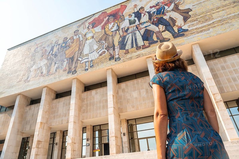 A female tourist looking at the painting of the entrance to the National Historical Museum in Skanderbeg Square in Tirana. Albania