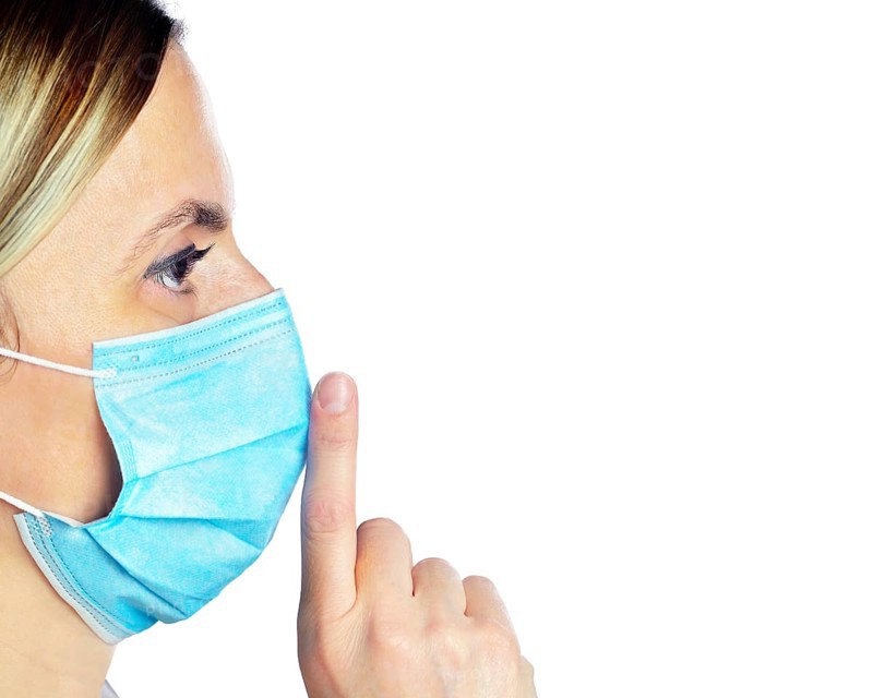 Woman wearing a face mask with her finger on her lips
