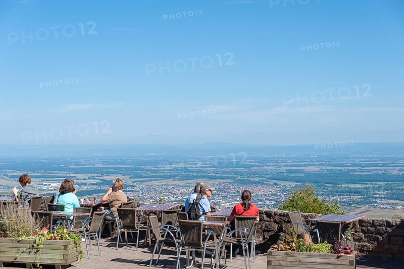 Tourists at the viewpoint in front of the Chateau du Haut Koenigsbourg. In the background the Upper Rhine Plain and the hilly landscape of the Black Forest