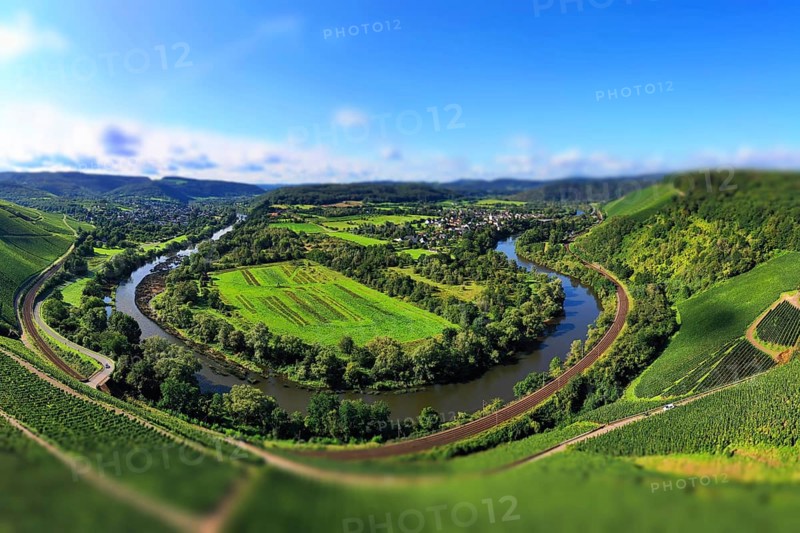 Wiltinger Saarbogen. The river winds through the valley and is surrounded by vineyards and green forests. Kanzem