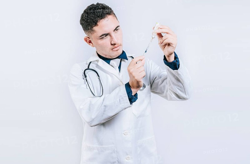Doctor drawing antidote from a vial. Concept of doctor with disease antidote. Handsome doctor drawing medicine from a vial with copy space