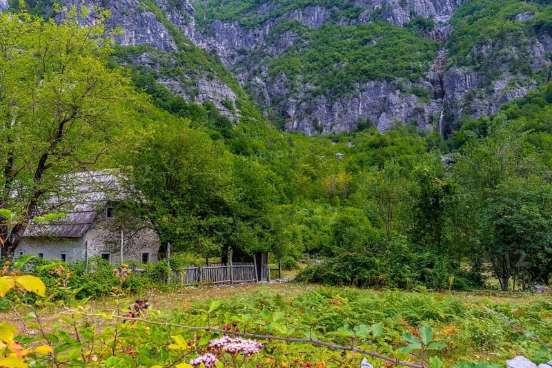 A wooden cabin under the Grunas waterfall in Theth National Park