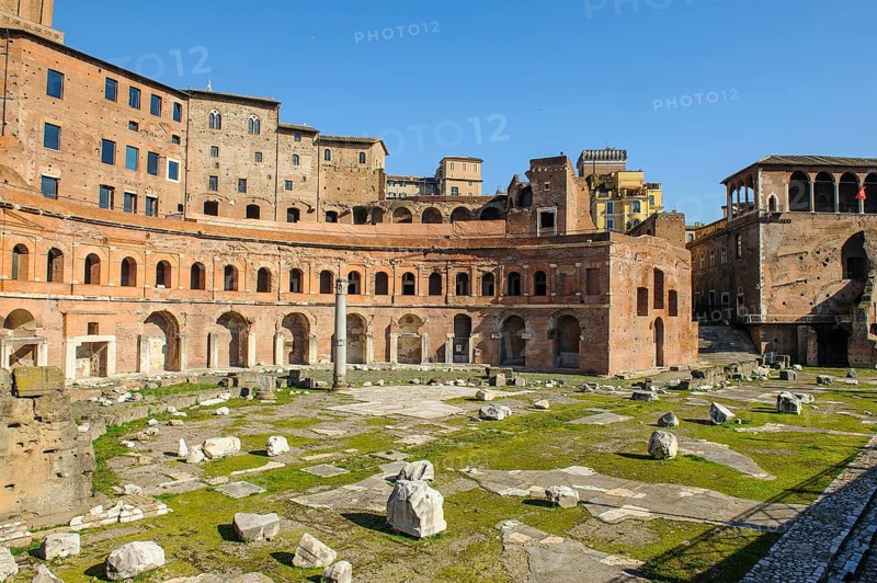 View of historic Forum of Traian Foro Traiano from antiquity with building in semicircle at rear with colonnade in foreground forecourt open space with column fragments remains of marble columns