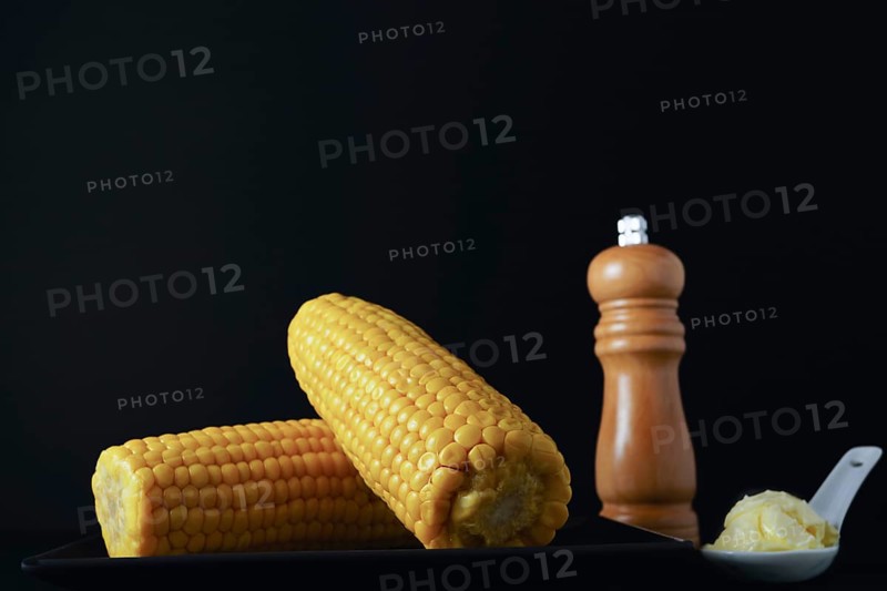 Corn cobs with pepper pot and spoon with butter