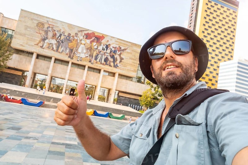 A male tourist at the entrance to the National Historical Museum in Skanderbeg Square in Tirana. Albania