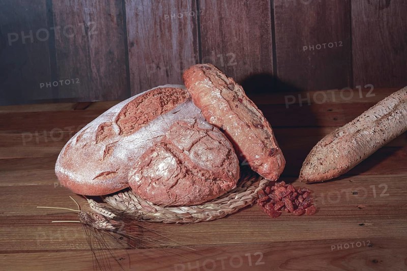 Loaf and loaves of rustic bread with ears of wheat on wooden table